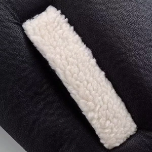 Gros plan détaillé du cuir noir de qualité cousu avec de la fourrure de mouton blanche