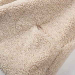 Close-up of beige faux shearling fabric texture on a stylish winter coat for women