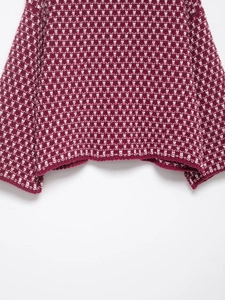 Detail of burgundy and white geometric knit texture on stylish long-sleeve cardigan
