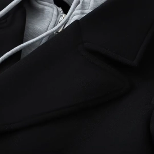 Detail of black lapel coat with grey detachable drawstring hood and silver metal zipper