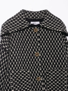 Close-up of black and white tweed knit cardigan with wide lapels and vintage buttons