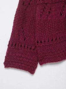 Macro shot of loose knit texture and hollow-out pattern on burgundy cardigan cuffs