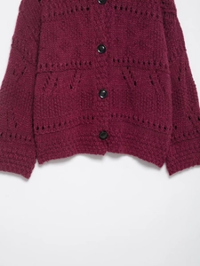 Close-up of chunky knit hollow-out texture and black buttons on a wine red cardigan