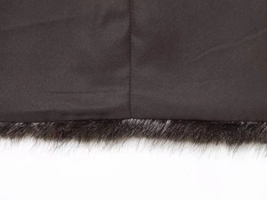 Detail shot of plush faux fur trim on a brown vest with neat stitching and fabric texture