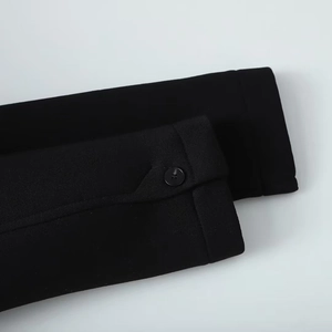 Detail of sleeve cuff on long black coat with button and clean stitching quality