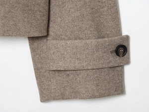 Détail de la manchette d'un manteau camel avec bouton texturé et patte de serrage