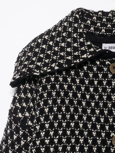 Detail of black and white textured knit cardigan with lapel and wood-style button