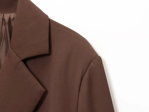 Detailed close-up of notched lapels and coffee brown twill fabric on tailored blazer