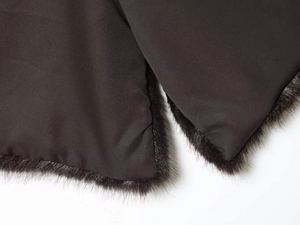 Detail of dark brown vest showing smooth twill fabric and premium faux fur trim texture