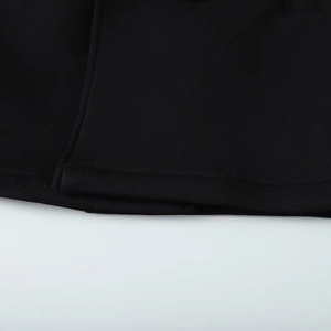 Close-up of the black long coat hem featuring precise stitching and high-quality fabric