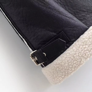 Détail de cuir grainé noir et doublure en laine blanche avec boucle en métal argenté