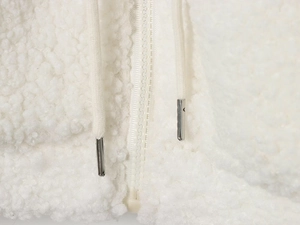Detail of white sherpa jacket showing smooth zipper and drawstring with metal tips
