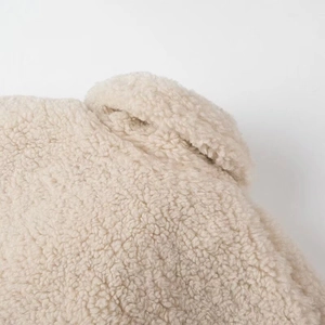 Detail shot of beige faux shearling coat showing thick curly plush texture and fine stitching