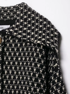 Macro detail of black and white tweed knit cardigan with lapel and button texture