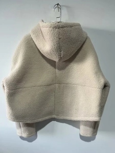 Détail d'une veste à capuche en polaire crème avec texture mouton et couture dorsale