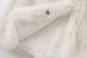 Detail of white faux fur vest showing soft satin lining and metal hook closure