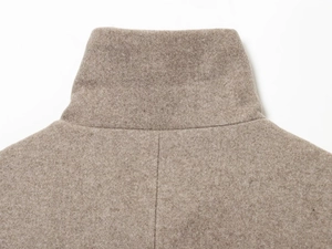 Détail du col d'une veste en laine marron clair montrant le tissu et les coutures de qualité
