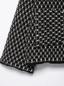 Close-up macro of black and white tweed knit fabric texture on a casual cardigan