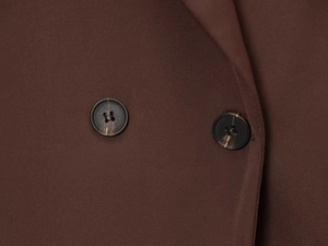 Detailed macro view of twill fabric texture and marbled buttons on dark brown blazer