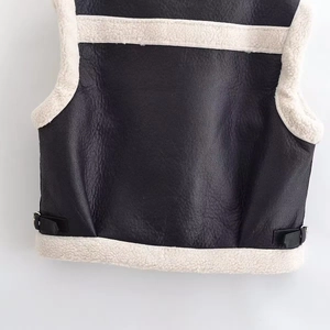 Détail du gilet en similicuir noir avec bordure en laine de mouton blanche et boucles