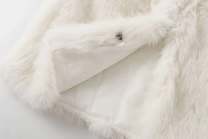 Detail of white faux fur vest showing soft plush texture and black metal hook closure