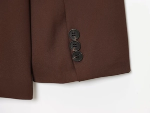 Detailed macro view of dark brown twill fabric with three classic resin buttons on the cuff