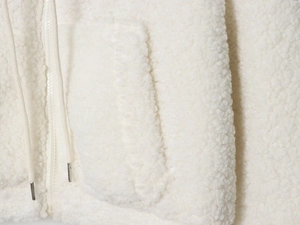 Detailed close-up of white fleece jacket featuring a metal-tipped drawstring and zipper