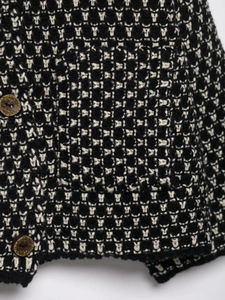 Close-up of black and white textured knit cardigan featuring marble-patterned brown buttons