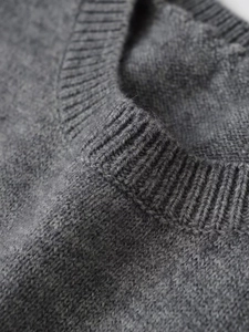 Dettaglio ravvicinato della maglia grigio scuro a coste con girocollo e morbida lana