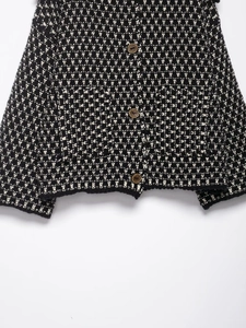 Detail view of monochrome knit cardigan texture with vintage brown buttons and black edges