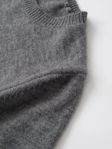 Dettaglio del girocollo a costine e della texture in lana del maglione in maglia grigia
