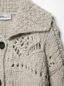 Detail of oatmeal chunky knit cardigan showing hollow-out texture and black buttons