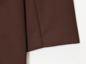 Close-up of deep brown twill fabric texture and detailed stitching on fashion blazer
