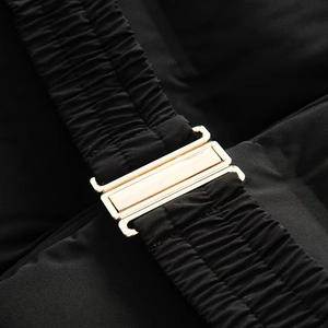 Detailed close-up of a black padded coat with an elastic waist belt and gold buckle