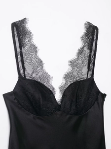 Detail eines schwarzen Satintops mit zarter Wimpernspitze und glatter Stofftextur