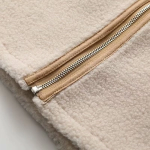 Détail de la texture polaire sherpa beige douce et fermeture éclair en métal argenté de qualité