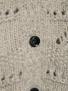 Detail of chunky knit cardigan with hollow pattern and marble texture button