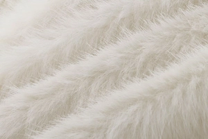 Detailed close-up of fluffy cream faux fur fabric texture showing soft synthetic fibers