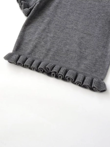 Dettaglio dell'orlo a balze su questo capo in maglia a coste grigio scuro