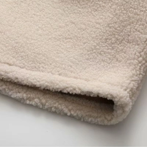 Gros plan sur la texture sherpa beige et les détails de couture de l'ourlet doux