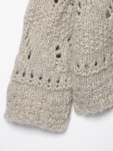 Detail of chunky knit cardigan featuring openwork patterns and ribbed cuffs in oatmeal