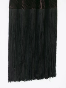 Detail view of the black velvet fabric and elegant long tassels on this evening dress