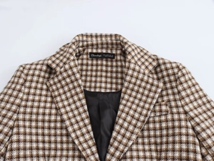 Detail view of the houndstooth pattern fabric and inner collar label on a long plaid coat