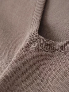 Détail du col en V sur pull en maille taupe montrant la texture côtelée et couture