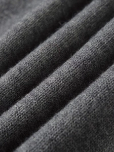 Macro dettagliata del tessuto a maglia grigio scuro che mostra la morbida trama di cashmere