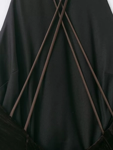 Detail of cross-strap back design on a black bandage dress with thin brown cords