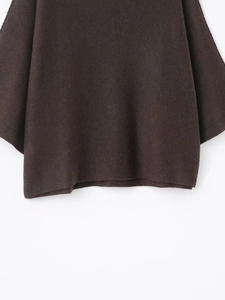Detail of dark brown knit sweater showing loose cuffs and hem against white background