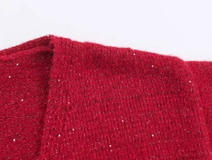 Detail shot of a red knitted cardigan featuring subtle silver sequins and a fuzzy texture