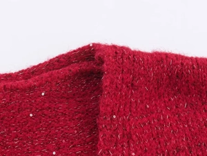 Close-up of red knit cardigan fabric with fuzzy mohair texture and shimmering sequins