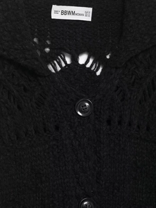 Close-up of black chunky knit cardigan featuring hollow-out details and round buttons